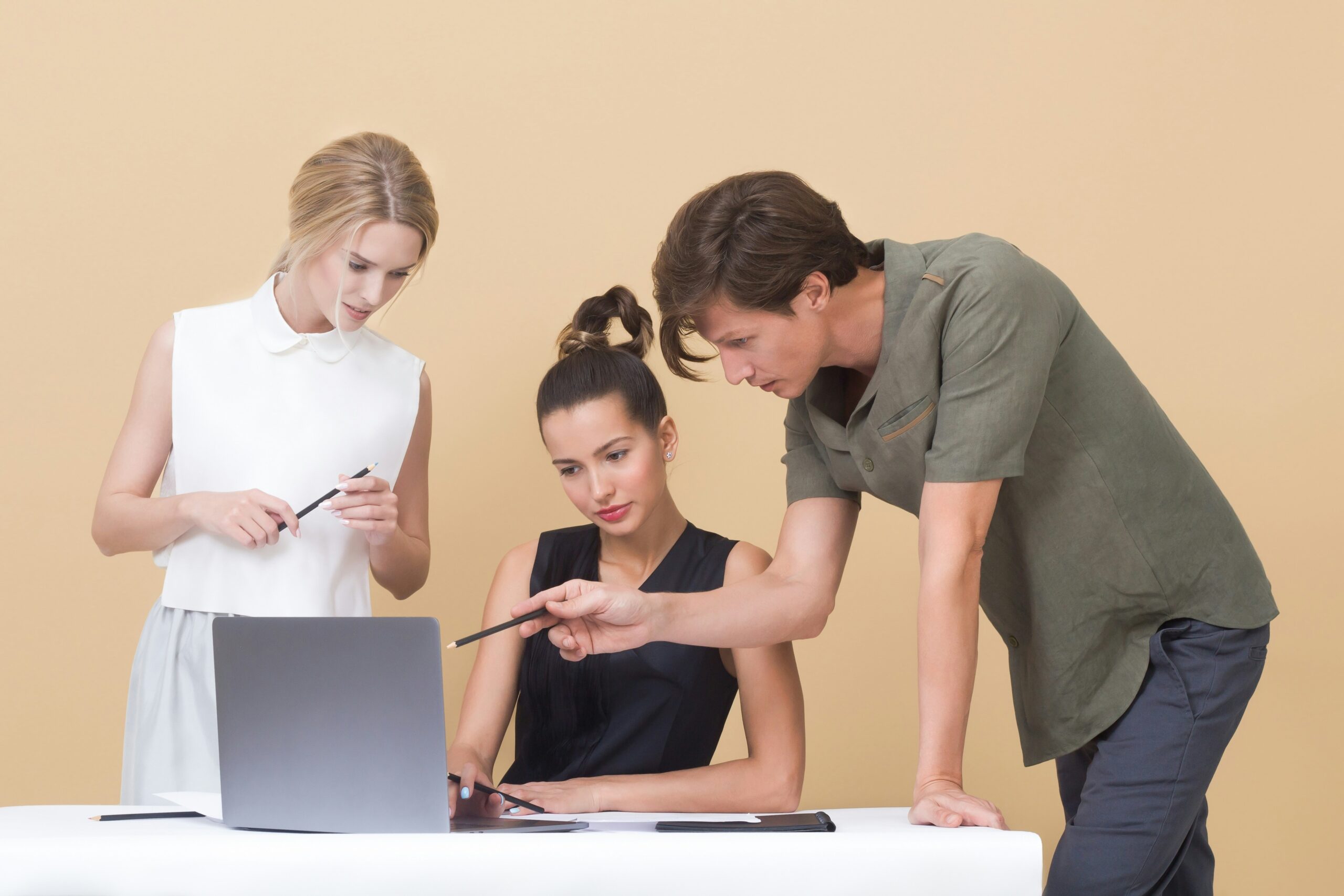 Three people discussing ideas in front of a laptop.
